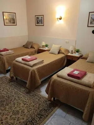 a room with three beds with brown blankets and a rug at KIN Hotel in Villa Carlos Paz