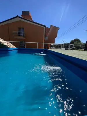 a pool of blue water in front of a house at KIN Hotel in Villa Carlos Paz