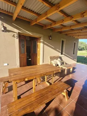 a wooden picnic table on a patio in front of a house at Brisas De Las Sierras in Villa Ciudad Parque