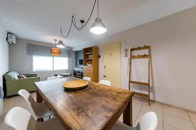 a dining room with a wooden table and white chairs at Gral Paz con patio privado y asador in Cordoba