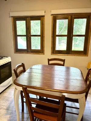 a wooden table in a kitchen with chairs and windows at La Ribera Aparts in Santa Rosa de Calamuchita