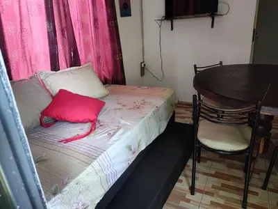 a small bed with a pink pillow next to a table at Departamentos sandry in Villa Carlos Paz