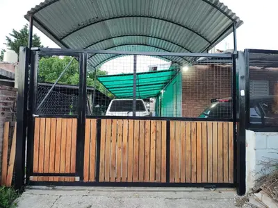 a wooden gate with a fence and a building at Departamentos sandry in Villa Carlos Paz