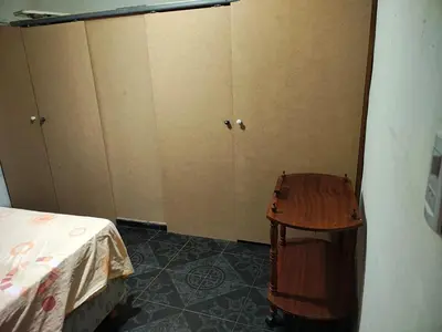 a room with a bed and a table and cabinets at Departamentos sandry in Villa Carlos Paz