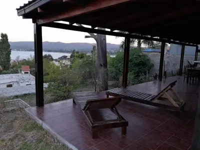 a wooden bench on a patio with a view of the water at La Morada de tus Sueños VCP con vista al LAGO in Villa Carlos Paz
