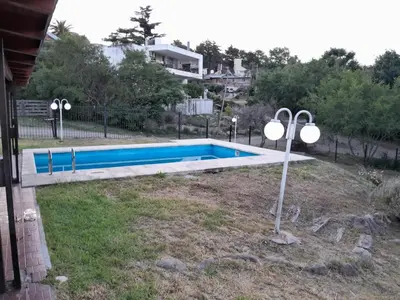 a swimming pool in a yard next to a house at La Morada de tus Sueños VCP con vista al LAGO in Villa Carlos Paz