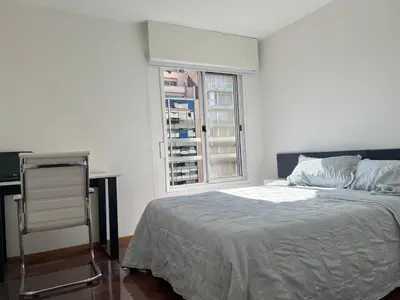 a white bedroom with a bed and a window at Departamento en Nueva Córdoba, Córdoba Capital in Cordoba
