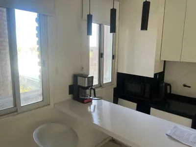 a white kitchen with a sink and two windows at Departamento en Nueva Córdoba, Córdoba Capital in Cordoba