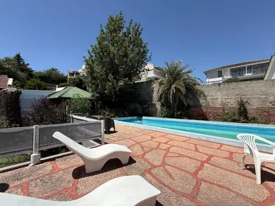 a swimming pool with two white chairs and a swimming pool at Casa TOKIO in Villa Carlos Paz