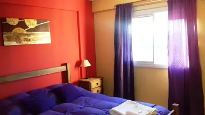 a bedroom with a bed and a window with purple curtains at Temporario en Villa Sol in Cordoba