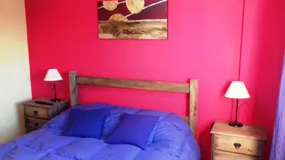 a bedroom with a bed and a pink wall at Temporario en Villa Sol in Cordoba