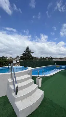 a swimming pool with stairs next to a swimming pool at Capri Hotel y Cabañas in Villa Carlos Paz