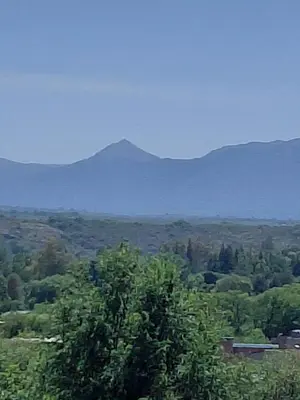 a tree in the foreground with mountains in the background at Mi Destino in Tanti Nuevo