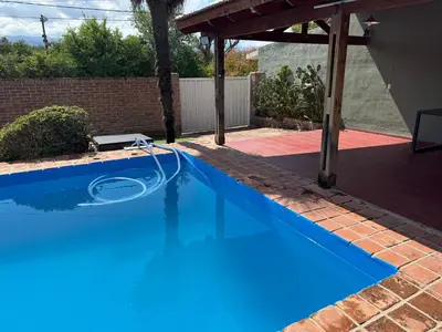 a swimming pool with a hose in a yard at Casa privada con piscina y quincho Altavip in Villa Cura Brochero