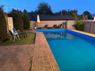 a large blue swimming pool with a table and chairs at Casa privada con piscina y quincho Altavip in Villa Cura Brochero