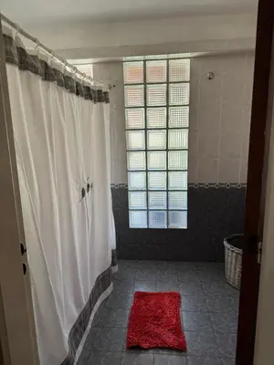 a bathroom with a shower and a red rug at Casa privada con piscina y quincho Altavip in Villa Cura Brochero