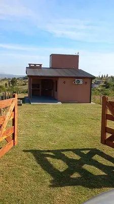 a building with a fence in front of a yard at La Tranquila in Villa Yacanto