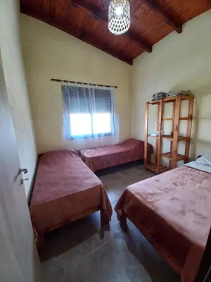 a bedroom with two beds and a window and a chandelier at La Tranquila in Villa Yacanto