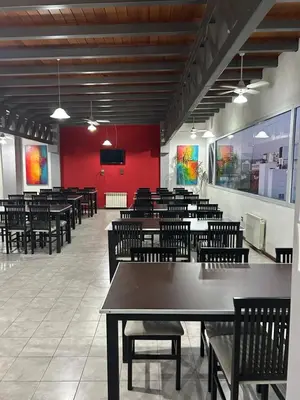 a dining room with tables and chairs and a red wall at Dpto Carlos Paz in Villa Carlos Paz