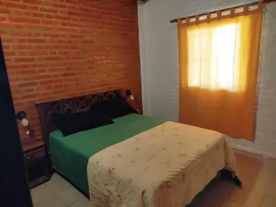 a bedroom with a bed and a brick wall at Shanti Cabañas in Mina Clavero