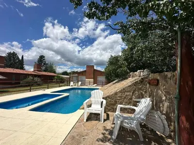two white chairs sitting next to a swimming pool at Shanti Cabañas in Mina Clavero
