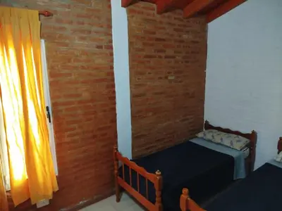 a bedroom with two beds and a brick wall at Shanti Cabañas in Mina Clavero
