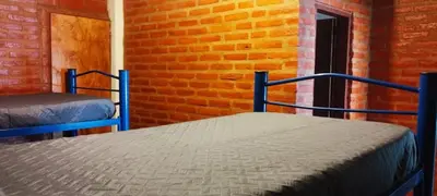 a bedroom with two beds in front of a brick wall at Habitación Compartida Tipo Hostel para los más aventureros in Nono