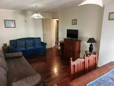 a living room with a blue couch and a tv at Departamento 2 dorm frente patio olmos in Cordoba