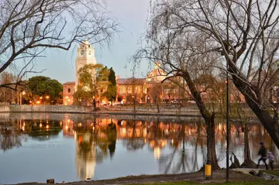 a building with a clock tower next to a lake at Departamento Valle de Luz in Alta Gracia