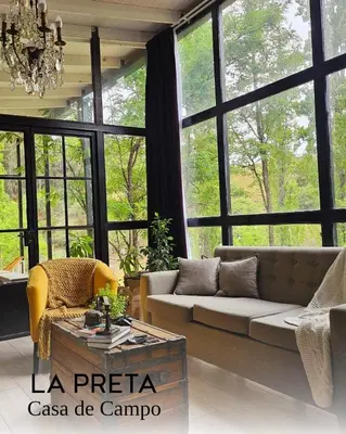 a living room with a couch and large windows at La Preta, casa de campo in San Clemente