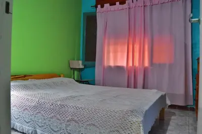a bedroom with a bed and a pink curtain at Departamento Parra in Panaholma
