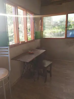 a room with a table and a chair and windows at Pie de Sierra in Los Hornillos