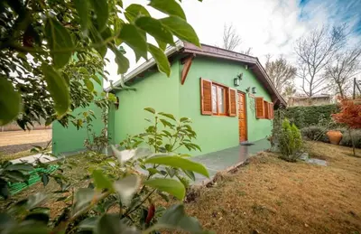 a green house with orange shutters on it at Tierras de Breena in Los Reartes