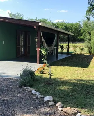 a green house with a hammock in front of it at Tierras de Breena in Los Reartes