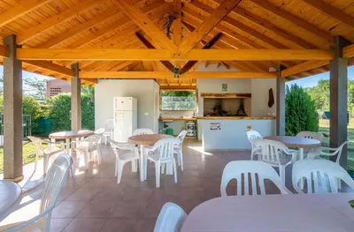 a covered patio with tables and white chairs at Tierras de Breena in Los Reartes