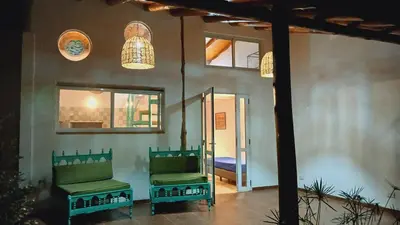 a porch with two green chairs and a room with a door at Pacha es Arte in Villa Ciudad Parque