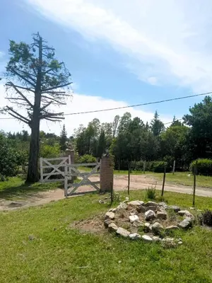 a field with a gate and a rock circle in the grass at Cabañas Las Pasionarias in Tanti