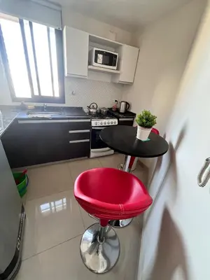 a small kitchen with a red stool and a table at Departamento 1 dormitorio con Piscina y Gran Vista en Nueva Cordoba in Cordoba