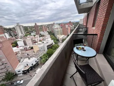 a balcony with a table and chairs and a view of a city at Departamento 1 dormitorio con Piscina y Gran Vista en Nueva Cordoba in Cordoba