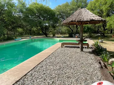 a pool with a bench and a straw umbrella at cabañas Gerom in Pantanillo