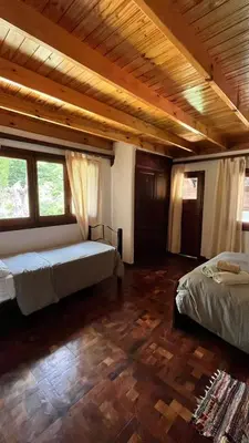 a bedroom with two beds and two windows at Hostel Cumbrecita Planeta in La Cumbrecita