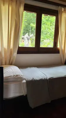 a bedroom with two beds and two windows at Hostel Cumbrecita Planeta in La Cumbrecita