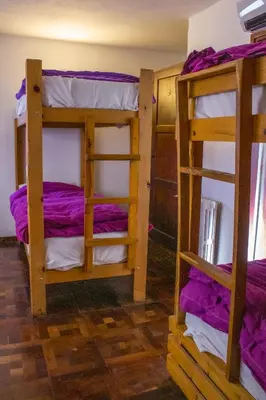 two bunk beds in a room with purple sheets at Hostel Cumbrecita Planeta in La Cumbrecita