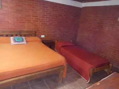 a room with two beds and a brick wall at Depto Villa Soto in Mina Clavero