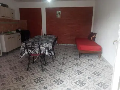 a dining room with a table and a red chair at Depto Villa Soto in Mina Clavero