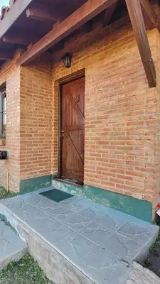 a brick building with a wooden door on it at Cabaña El Molle - Los Nogales in Mina Clavero