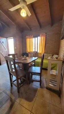 a dining room with a table and chairs and a bed at Cabaña El Molle - Los Nogales in Mina Clavero