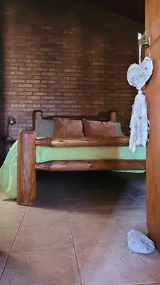 a wooden bed in a room with a brick wall at Cabaña El Molle - Los Nogales in Mina Clavero