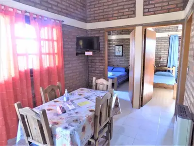 a dining room with a table and a bedroom at Cabañas La Morada de Tanti in Tanti