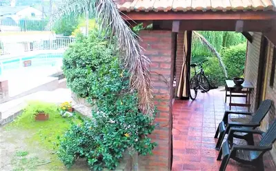 a building with a hedge with chairs and a pool at Cabañas La Morada de Tanti in Tanti
